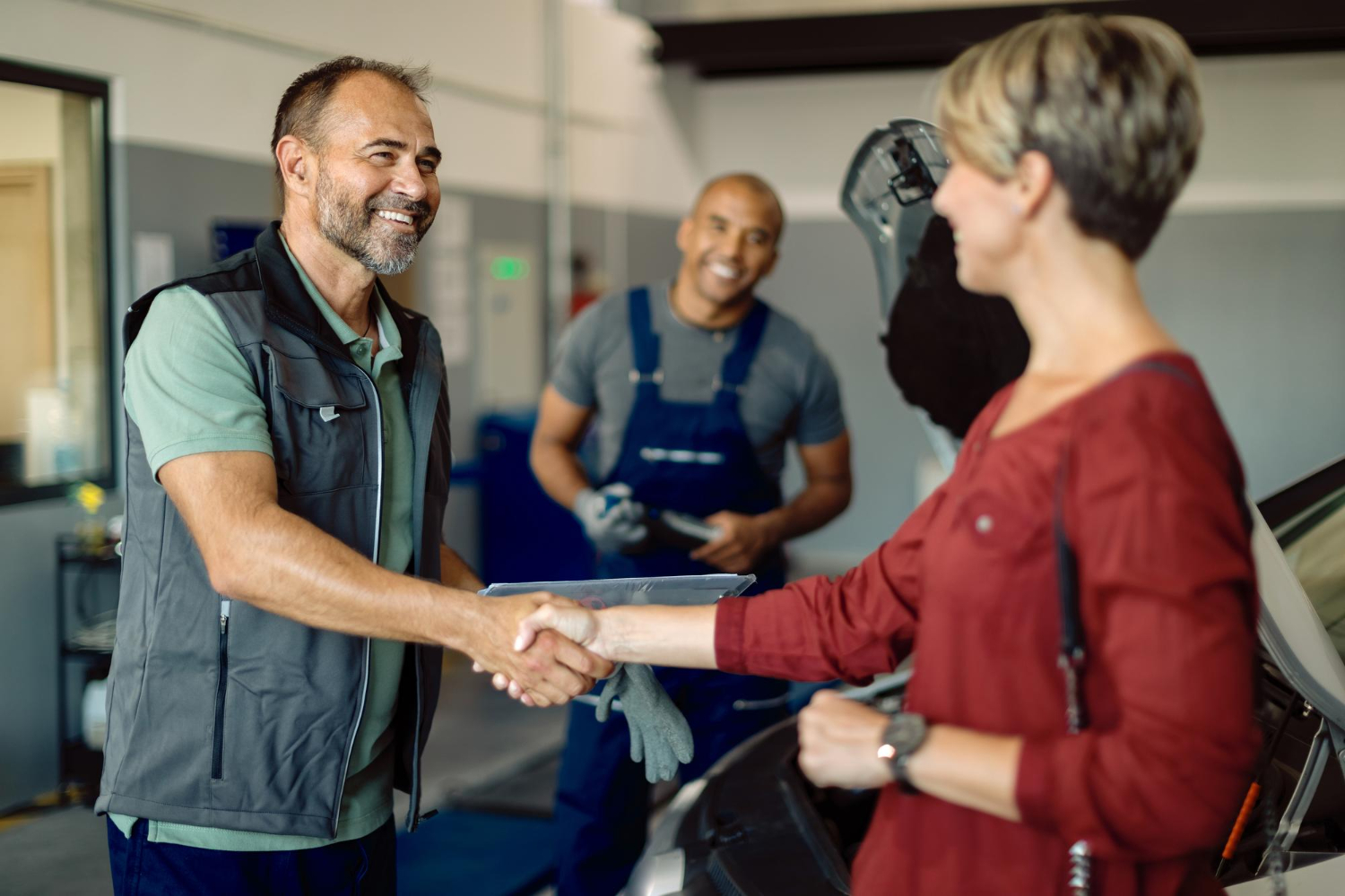 happy-mechanic-handshaking-with-female-customer-auto-repair-shop (1)